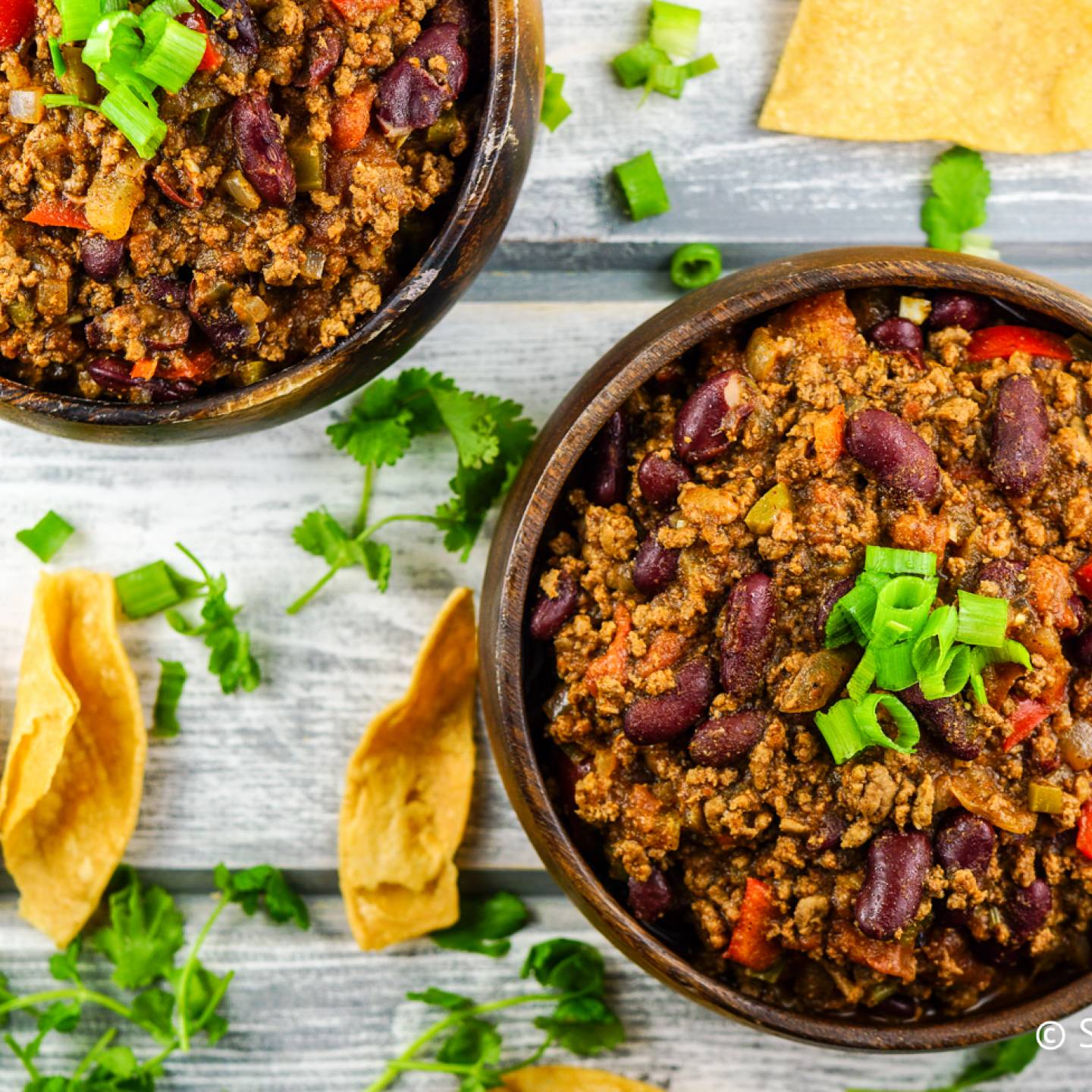 Healthy Turkey chili in two bowls with cilantro and tortilla chips.