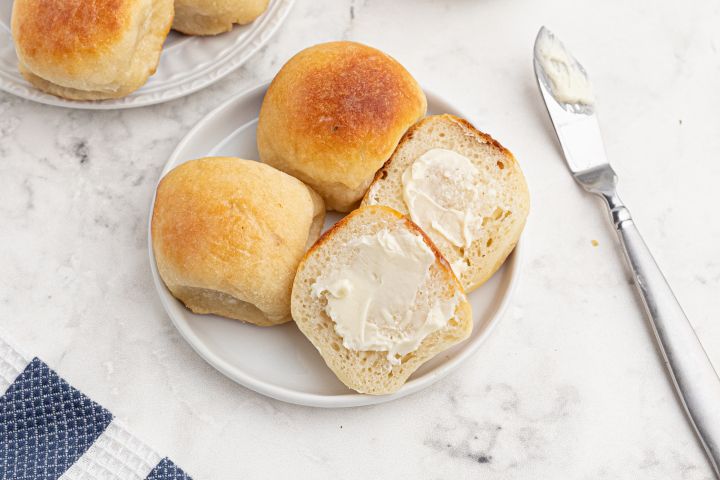 Easy dinner rolls made with two ingredient dough and served sliced in half with butter.