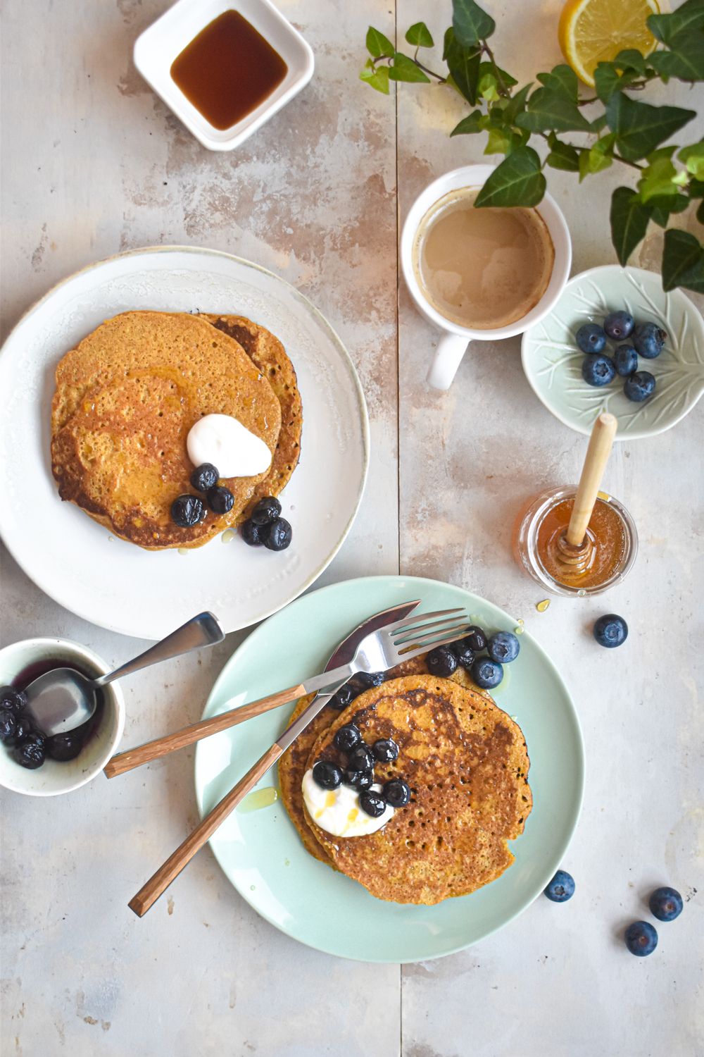 Flaxseed pancakes on two plates with yogurt and berries.