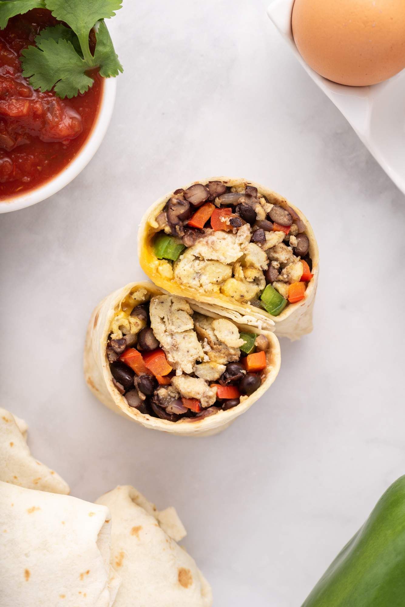 Breakfast burritos with eggs, black beans, peppers, and cheese wrapped in a tortilla.