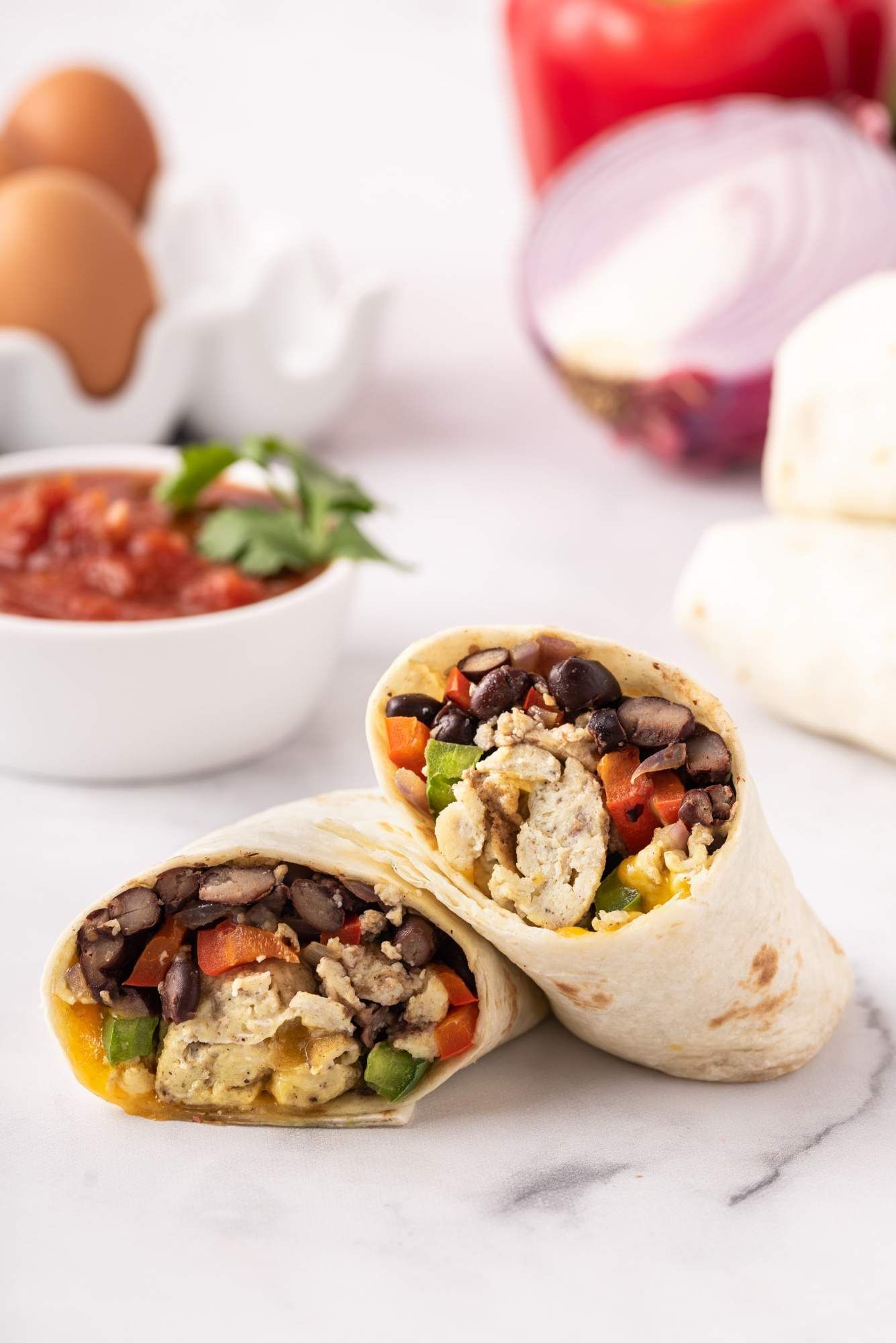 Egg burritos with black beans, peppers, and scrambled eggs wrapped in a tortilla with cheese.