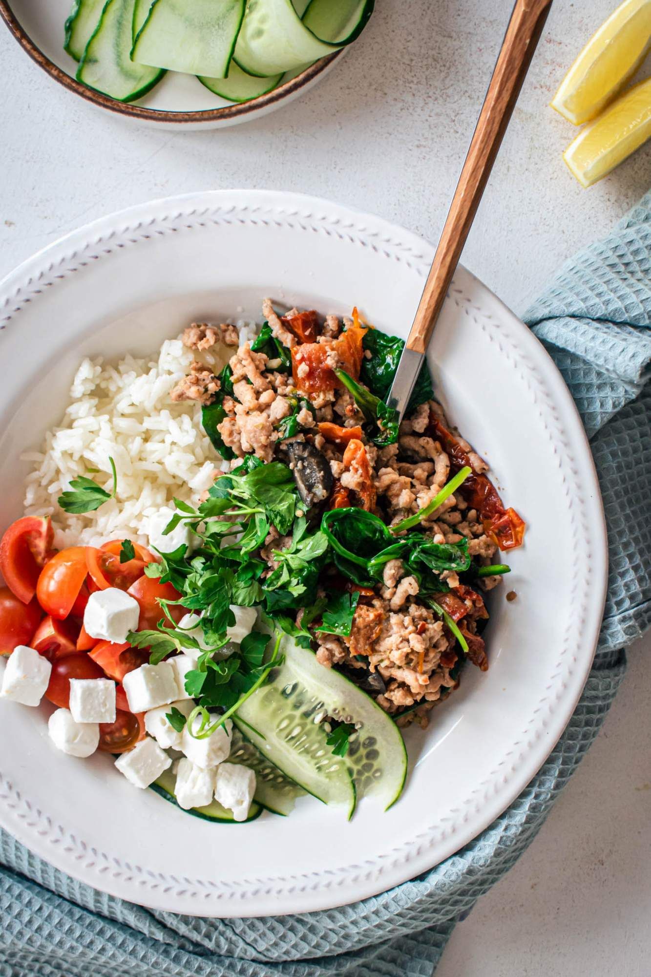 Ground turkey with kalamata olives, sundried tomatoes, feta cheese, and spinach in a bowl. 