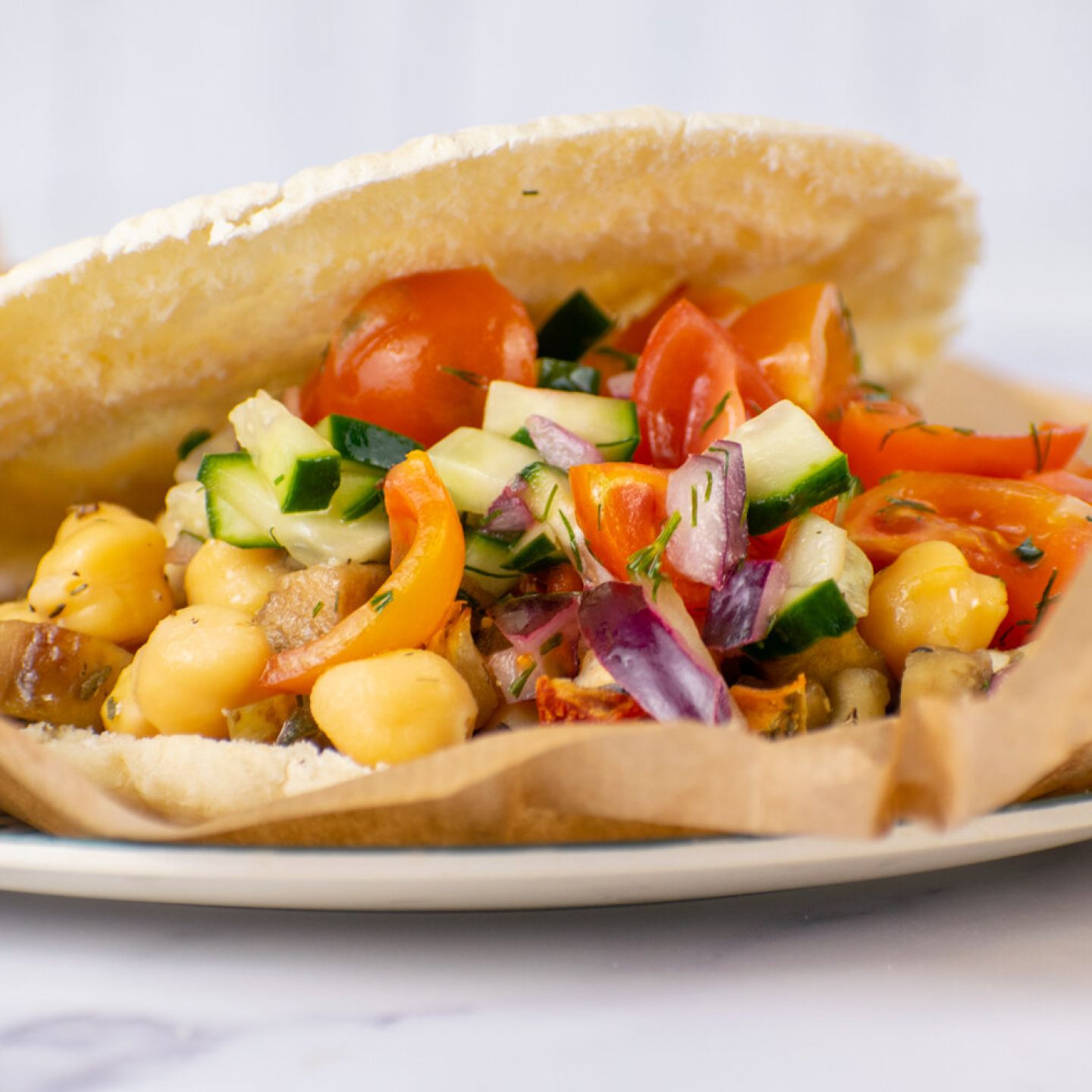 Greek tostadas with chickpeas, eggplant, tomatoes, red onions, and cucumbers on toasted pita bread.