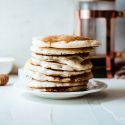 Greek yogurt stacked on a plate with maple syrup and coffee on the side.