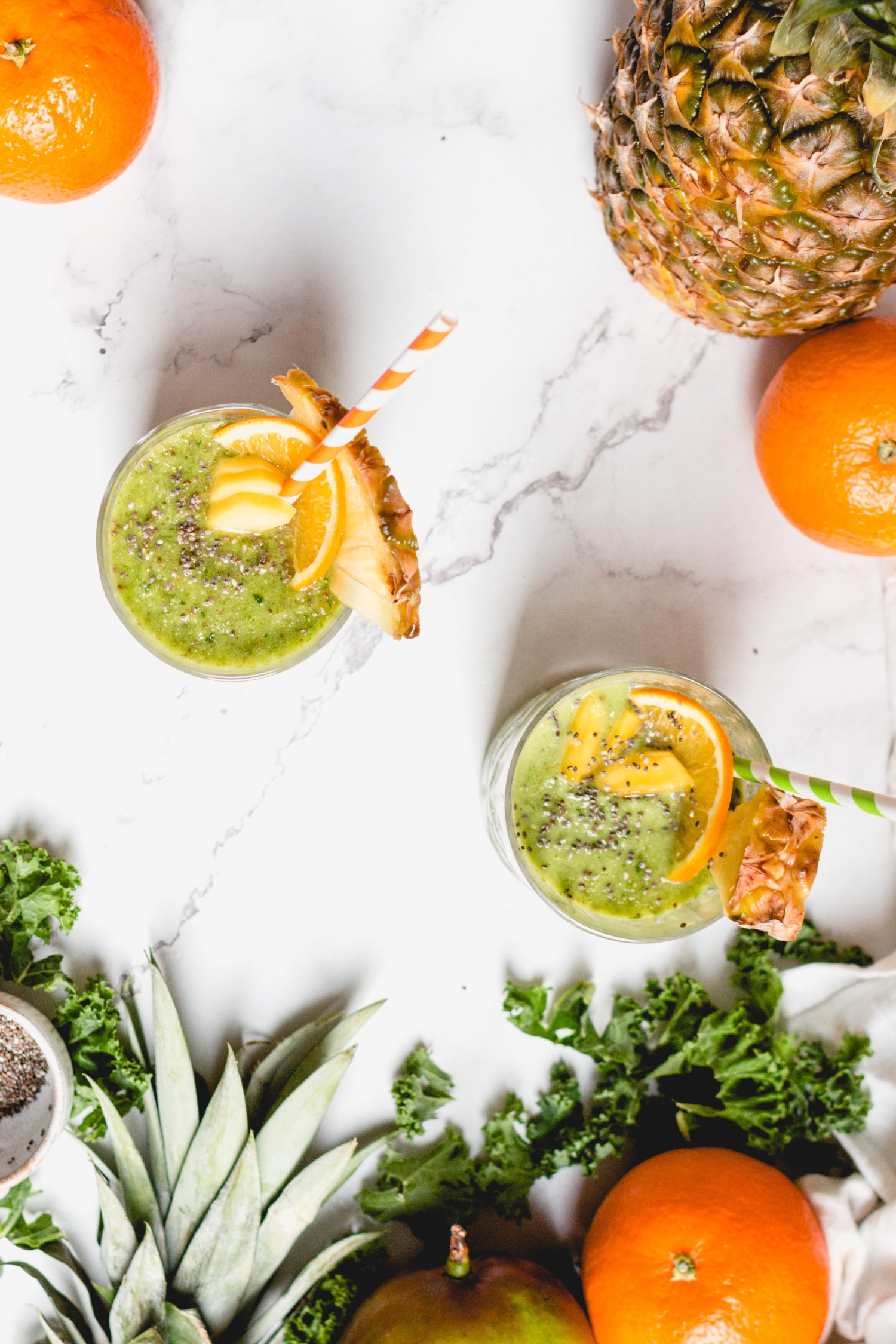 Banana free green smoothie with pineapple, mango, orange, and kale in two glasses.