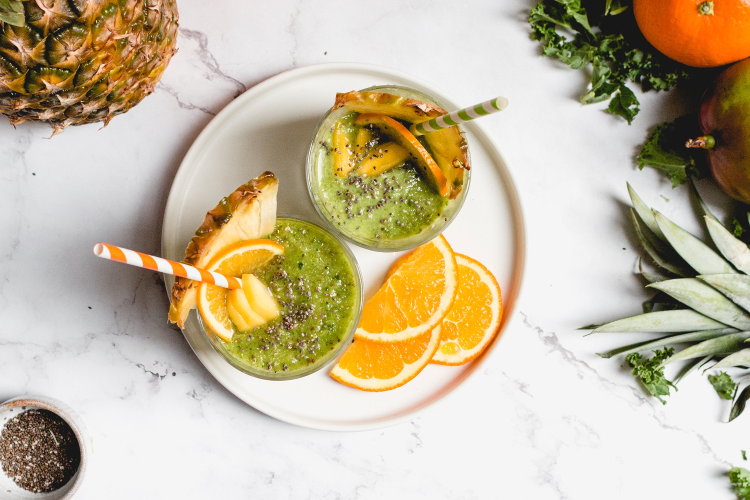 Green smoothie without bananas in a glass with chia seeds and mango on tops.