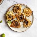 Grilled cabbage slices on a plate with grill marks with limes, salt, and grill seasoning. 