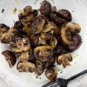 Grilled mushrooms with balsamic vinegar, olive oil, and garlic on a plate.