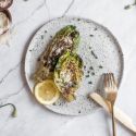 Grilled romaine lettuce on a plate with lemon, Parmesan, olive oil, and vinegar.