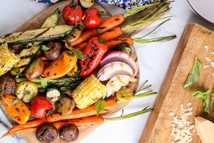 Grilled vegetables including carrots, zucchini, asparagus, corn, tomatoes, mushrooms, peppers, and red onion.