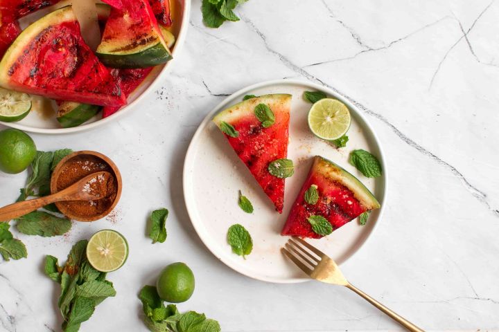 Grilled watermelon with grill marks served with fresh mint, lime juice, sea salt, and chili powder.