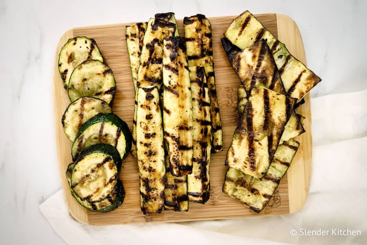 Grilled zucchini with garlic on a cutting board.