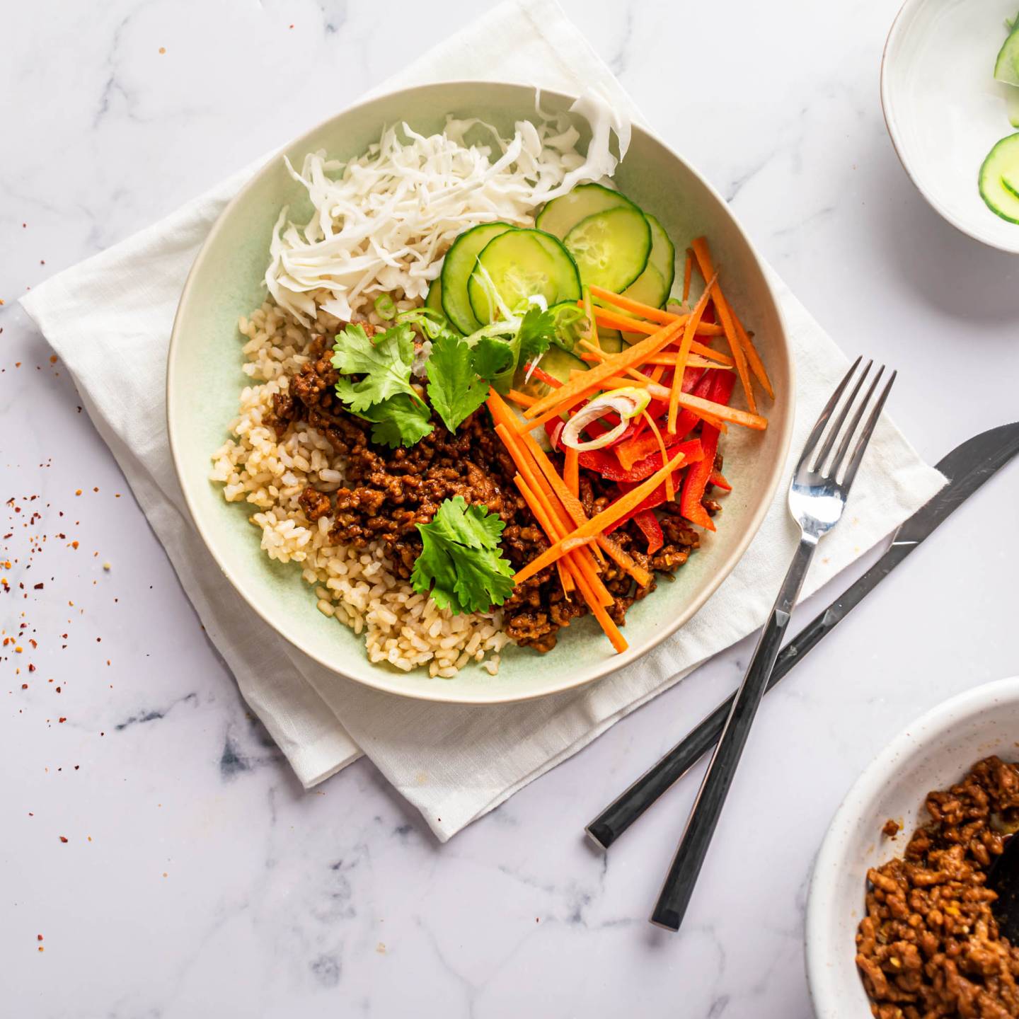 Ground beef bulgogi bowls with Korean flavored beef, cucumbers, carrots, red peppers, cabbage, and rice in a bowl. 