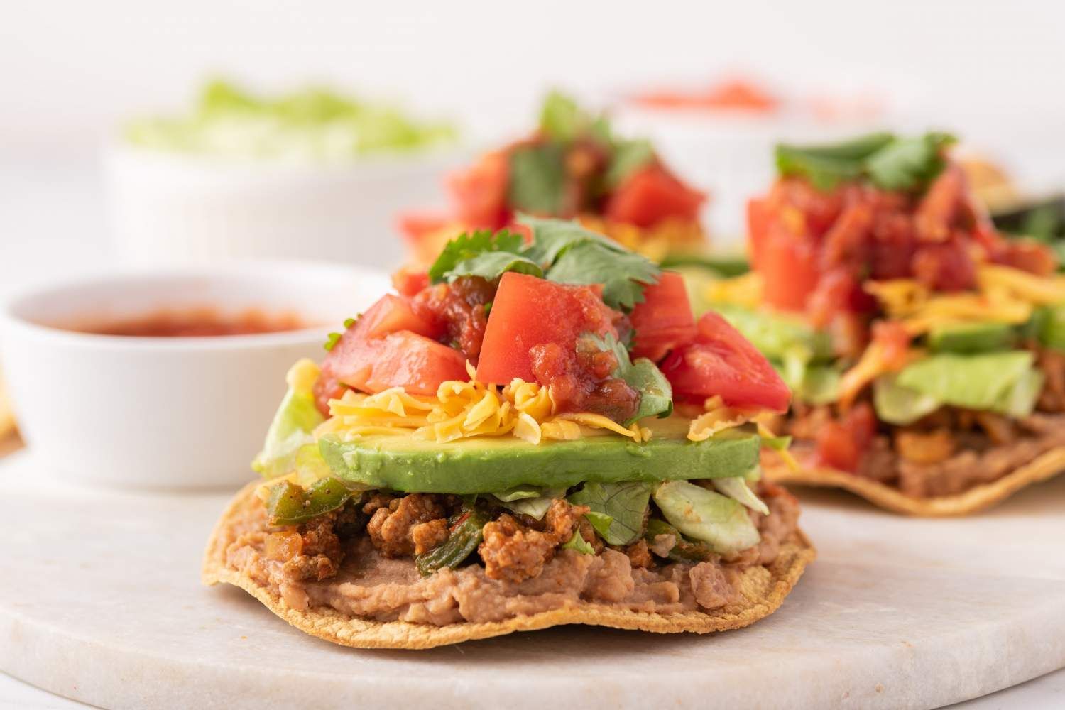 Ground turkey tostadas with beans, ground turkey, avocado, tomatoes, cheese, and cilantro.