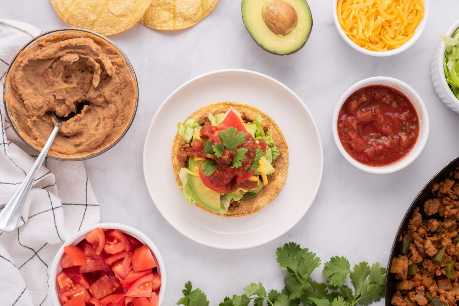 Turkey tostada with ground turkey, salsa, avocado, refried beans, and cilantro on a crispy corn tortilla.