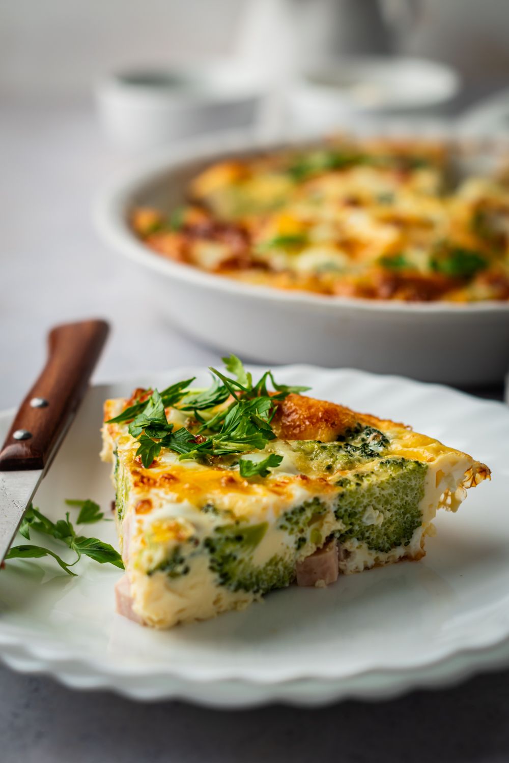 Frittata with ham, cheese, and broccoli sliced and served on a plate with parsley.