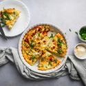 Ham and cheese frittata with broccoli cooked in a pie dish with a slice cut on the side. 