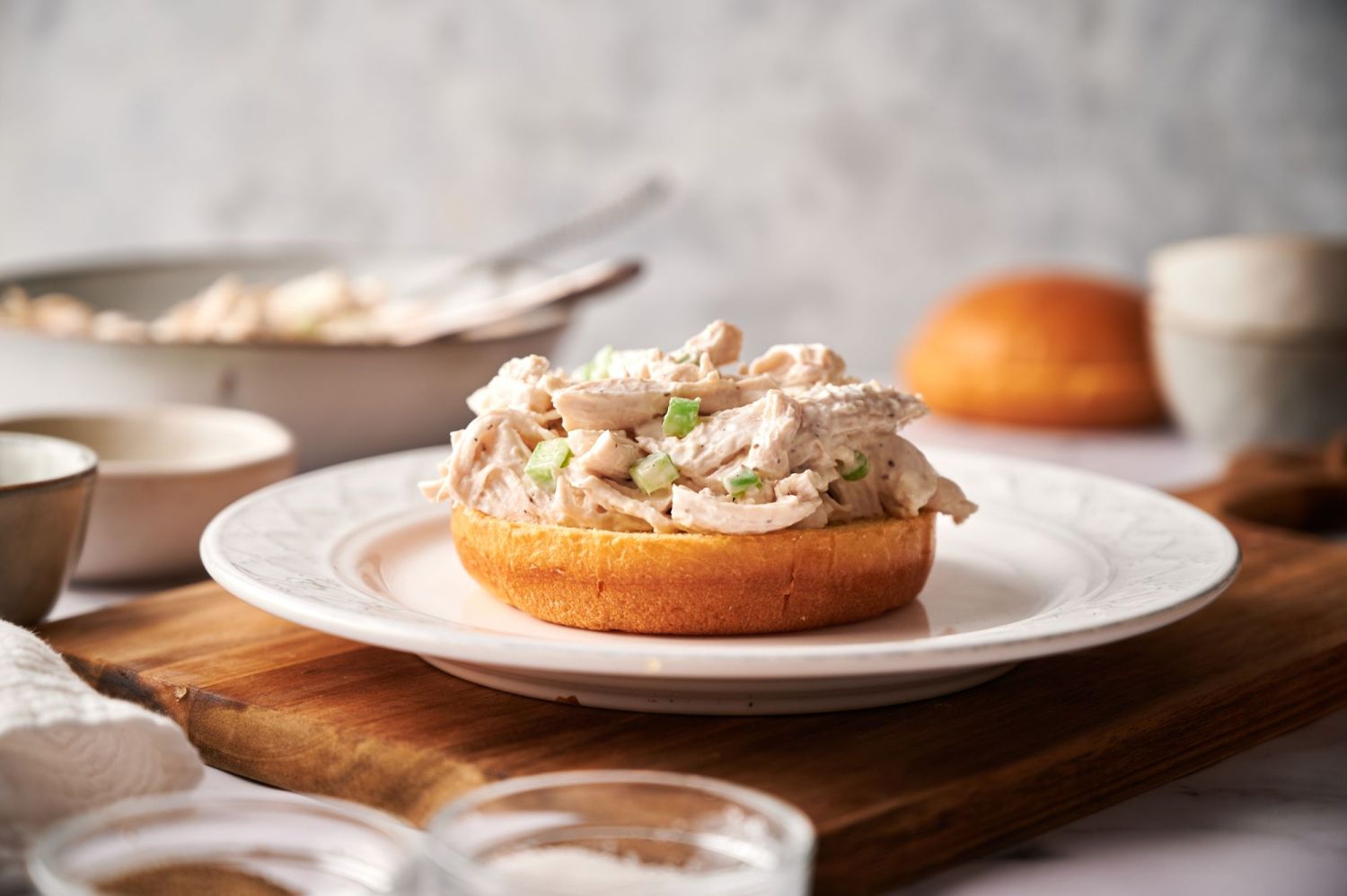 Chicken salad made with yogurt served open-faced on a white roll.