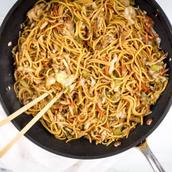 Chinese Chow mein with cabbage, noodles, and celery in soy sauce in a pan.