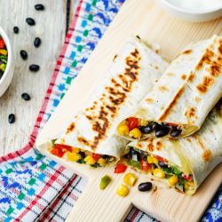 Homemade frozen burritos with beans, rice, and vegetables on a plate.