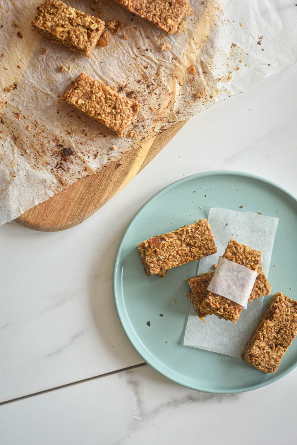 Oatmeal bars with peanut butter, bananas, and dates cut into bars and served on a blue plate with parchment paper.