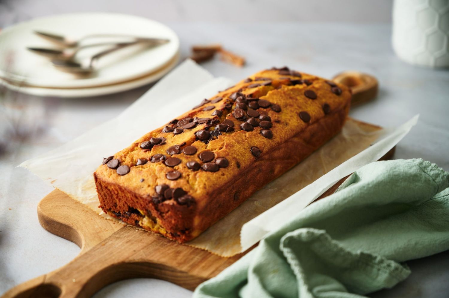 Healthy pumpkin bread with chocolate chips on a cutting board with parchment paper.