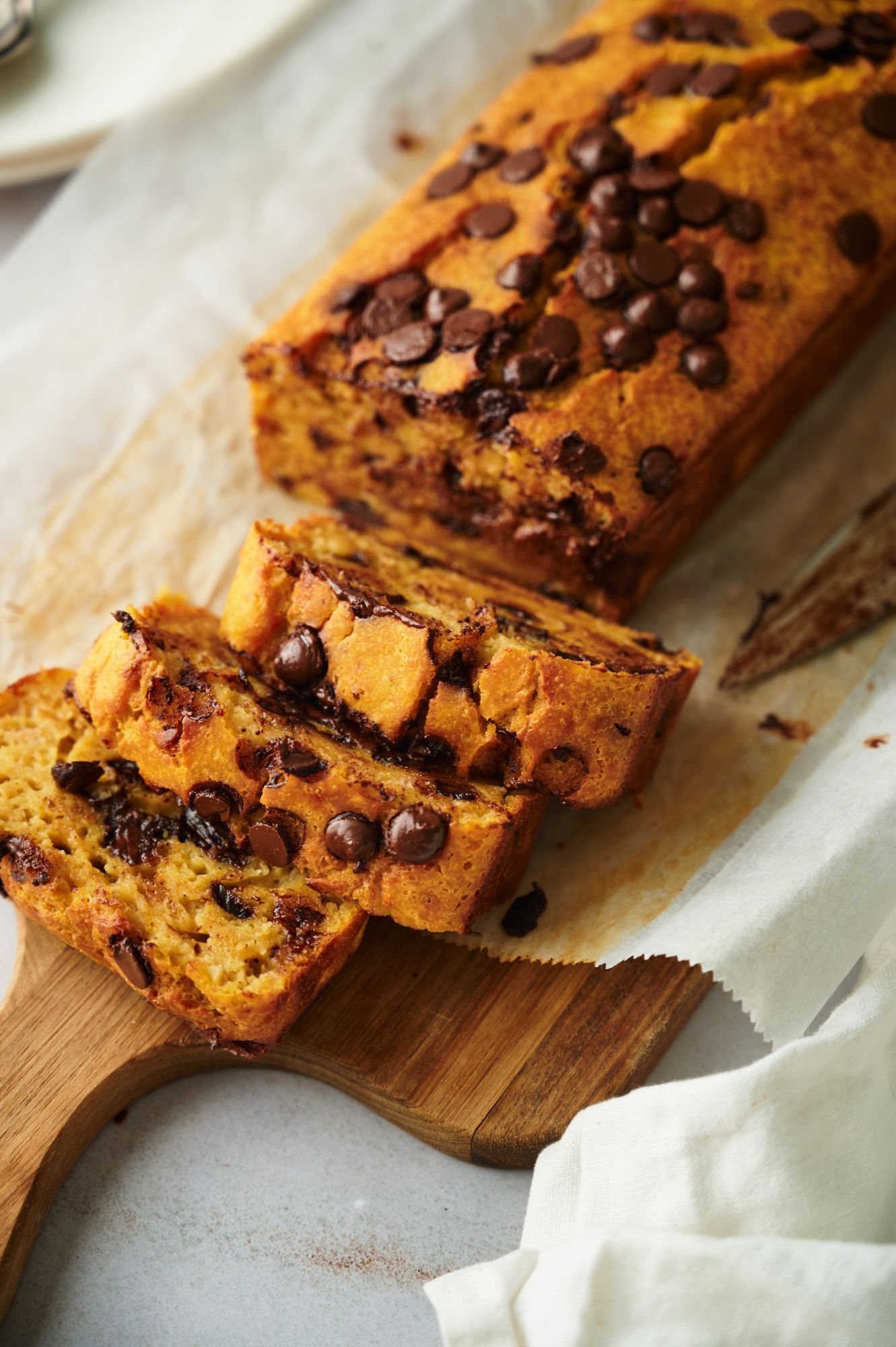 Pumpkin chocolate chip bread sliced on a wooden cutting board.