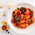 Honey garlic roasted carrots in a bowl with parsley. 