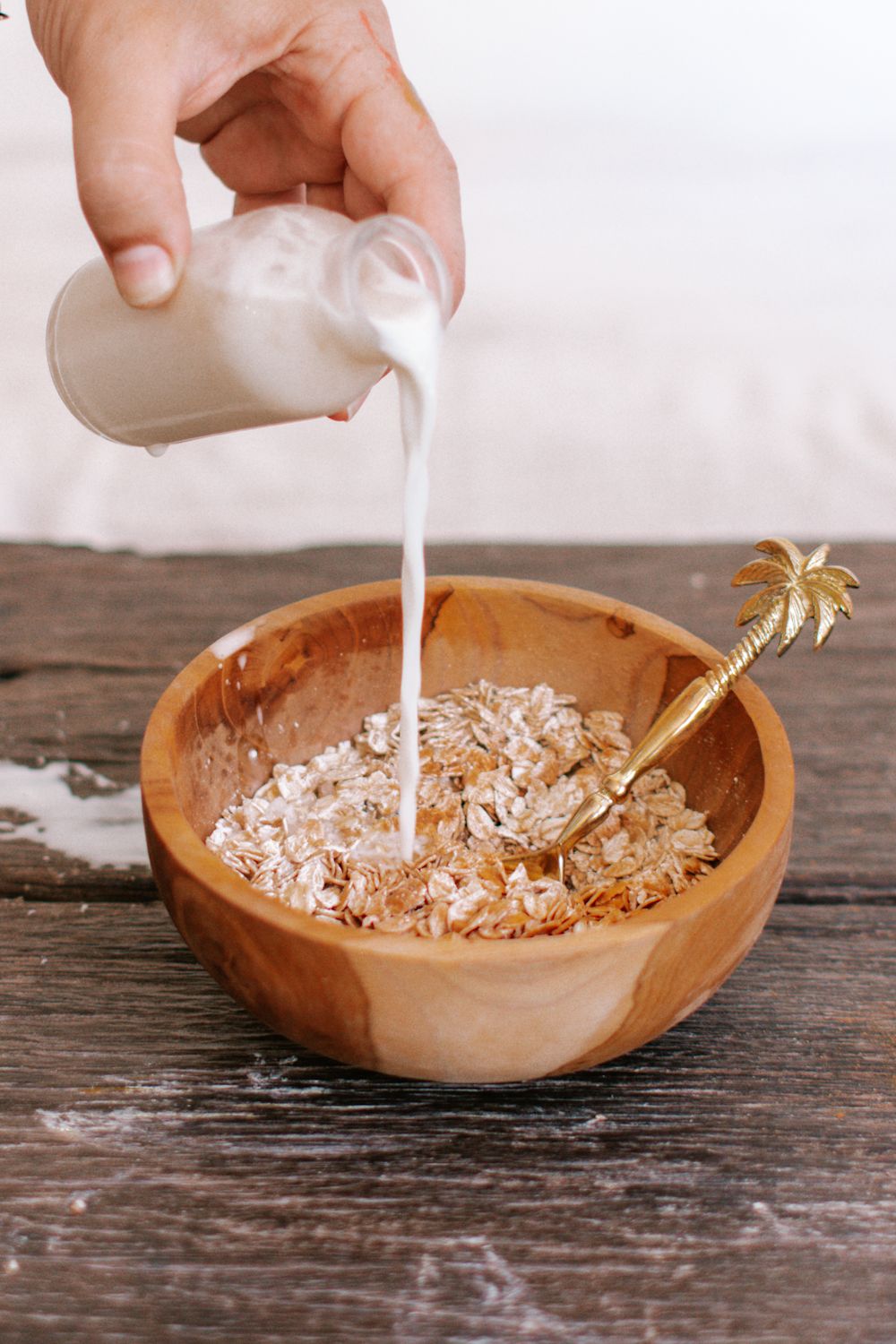 Easy overnight oatmeal in a bowl with almond milk being poured on top.