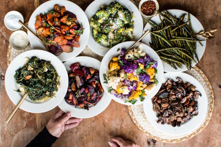 Roasted vegetables including broccoli, cauliflower, mushrooms, beets, and Bok choy on a wooden table.