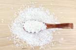 White rice on a wooden surface and a wood spoon