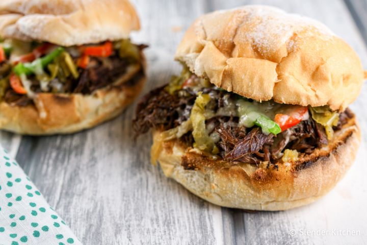 Instant pot drip beef on rolls with melted cheese, peppers, and a crust white roll.