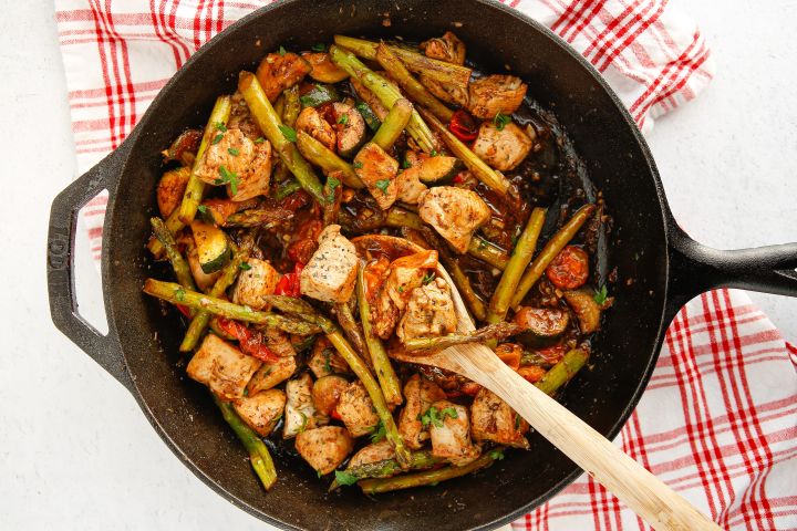 Italian chicken and vegetable skillet in a pan with chicken breast, asparagus, zucchini, parsley, and fresh lemon.