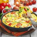 Italian breakfast frittata with arugula, roasted red peppers, eggs, and cheese in a baking dish.