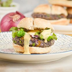 Jalapeno cheddar black bean burgers on a bun with lettuce, tomato, and onions.