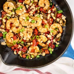 Kung Pao Shrimp with peanuts, celery, red peppers, and green onions in a skillet.