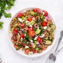 Easy lentil salad with Mediterranean flavors including olives, feta cheese, tomatoes, cucumbers, and fresh herbs in a bowl.