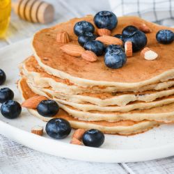 Low carb pancakes on a plate with blueberries and almonds.