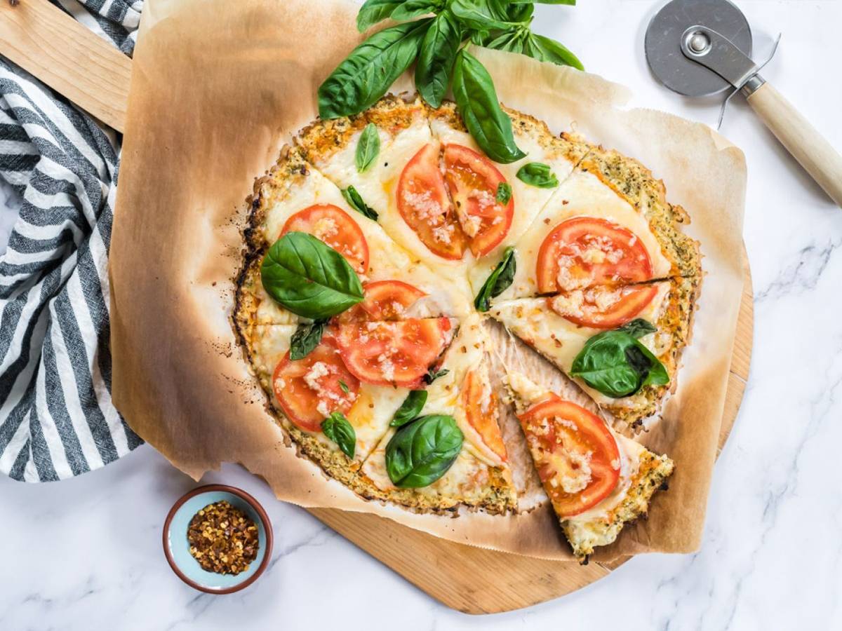 Cauliflower crust pizza made with cauliflower florets and topped with mozzarella cheese, tomatoes, and basil for a low carb pizza.