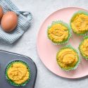 Low carb coconut muffins made with coconut flour on a pink plate with a muffin tin on the side.