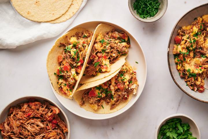 Machaca con huevo with scrambled eggs, beef machaca, tomatoes, onions, jalapeno peppers, and cilantro served in corn tortillas.