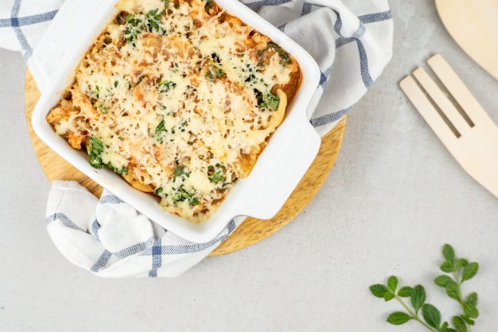 Mediterranean Turkey Spaghetti Squash with spinach, tomatoes, lean ground turkey, and melted cheese in a casserole dish.