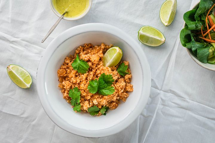 Mexican cauliflower rice with fresh cilantro, limes, and salsa on the side.