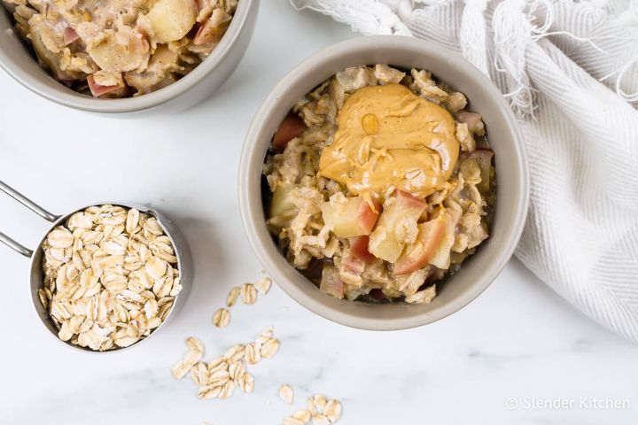 Microwave apple oatmeal with peanut butter and cooked apples in a bowl with cinnamon.