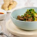 Moo Shu beef stirfry with sliced cabbage and cilantro in a blue bowl.