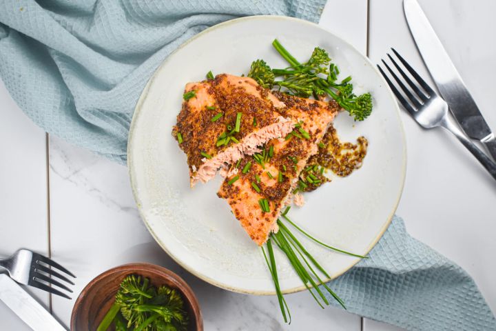 Mustard and maple glazed salmon with a honey mustard style sauce on a plate with broccolinl.