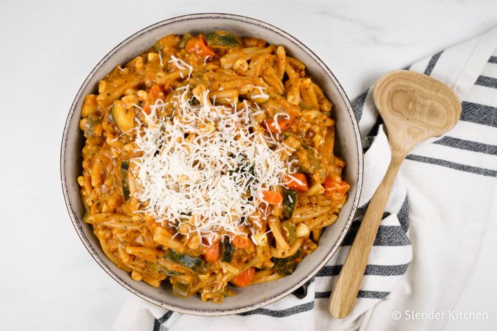 One pot creamy vegetable pasta with tomato sauce in bowl with mozzarella cheese.