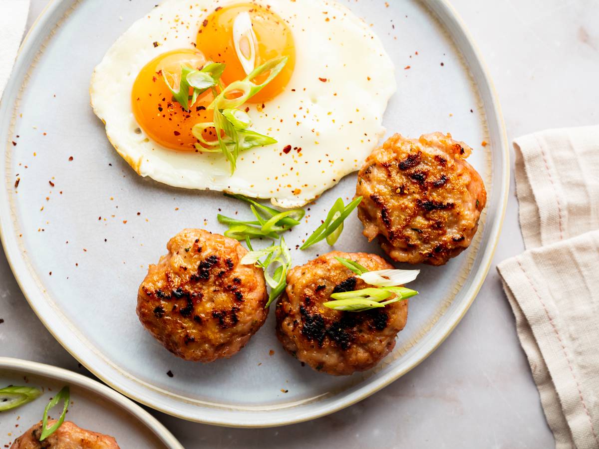 Turkey breakfast sausage served on a plate with sunny side ip eggs and green onions.