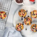 Pancake muffins with fresh fruit on a plate with a wire rack on the side.