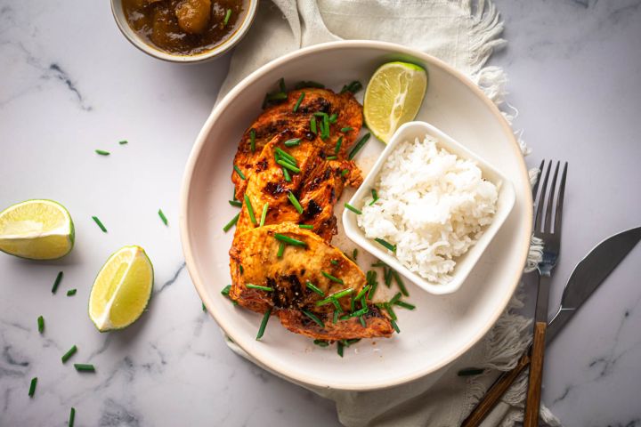 Paprika lime chicken breast served with white rice and sliced lime wedges.